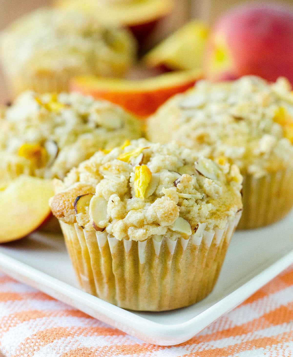 Moist and tender peach muffins, accented with almond extract and topped with a sweet and crunchy almond streusel. via @frshaprilflours