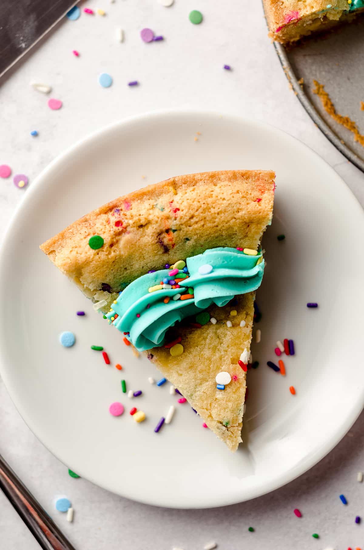 aerial photo of a slice of funfetti sugar cookie cake on a plate
