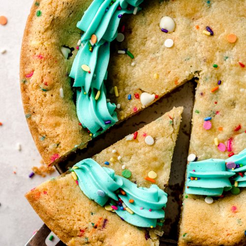 aerial photo of funfetti sugar cookie cake with a slice being taken out of it