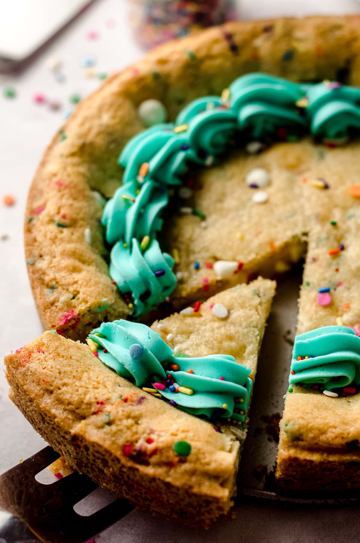 funfetti sugar cookie cake with a slice being taken out of it