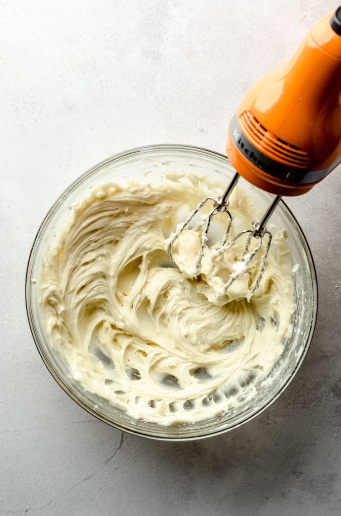 Aerial photo of cream cheese blended with an electric mixer.