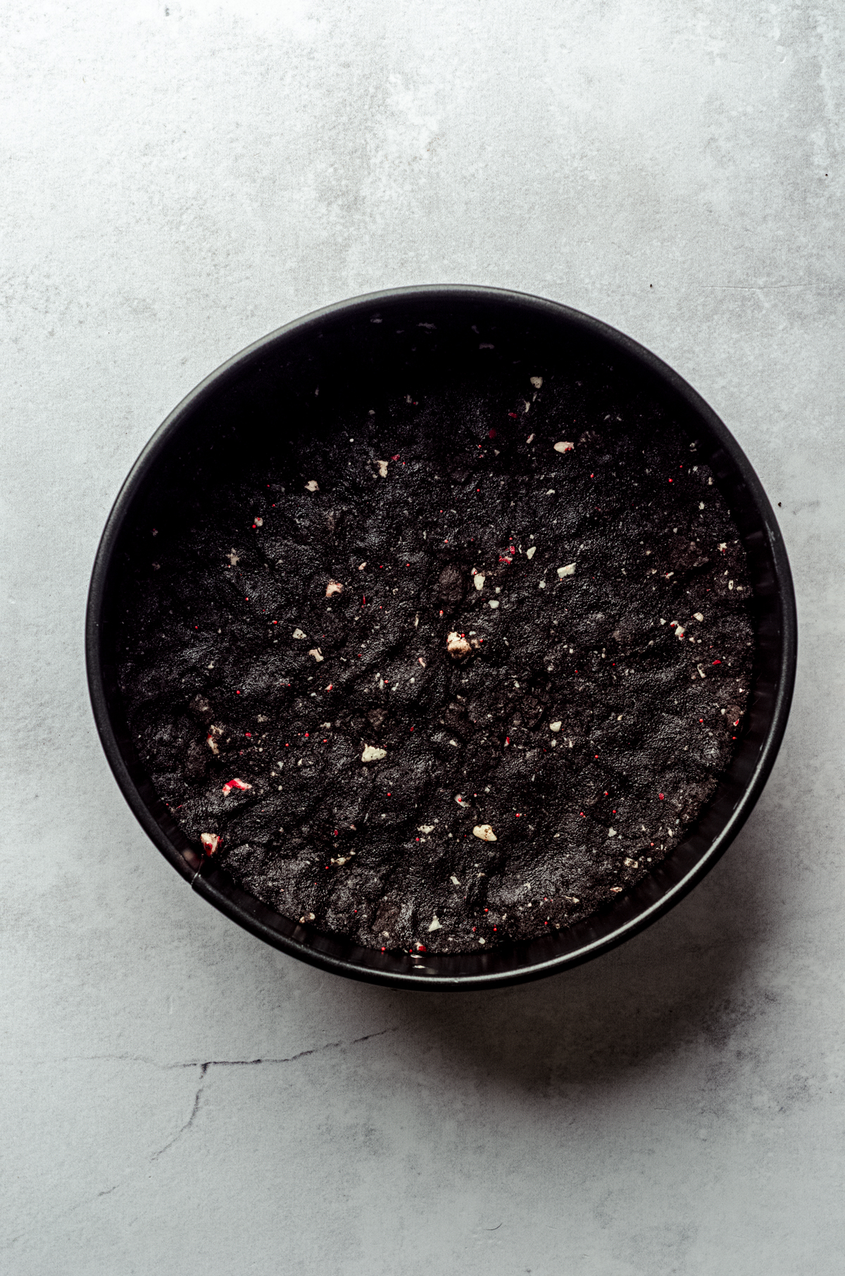 Aerial photo of a peppermint Oreo crust pressed into a springform pan.
