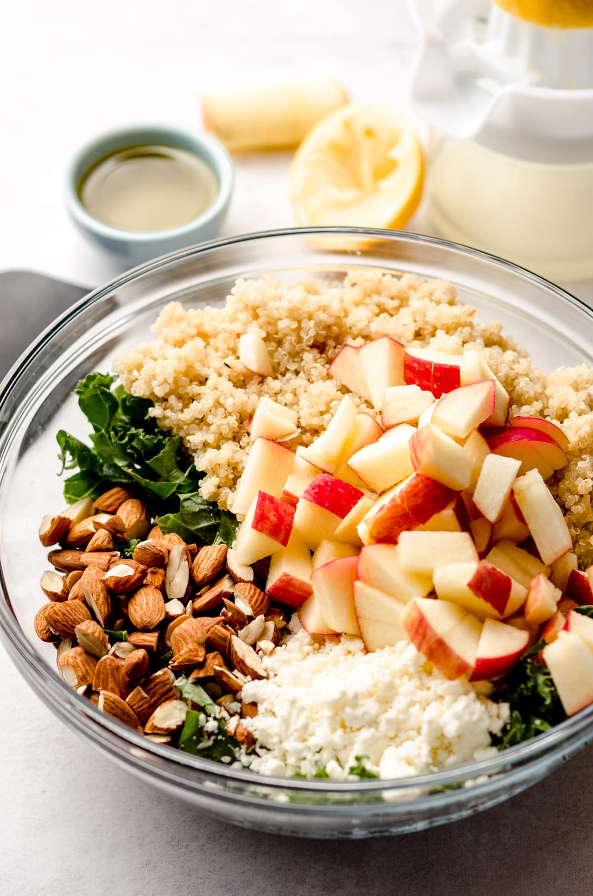 ingredients for apple, quinoa, and almond kale salad in a bowl