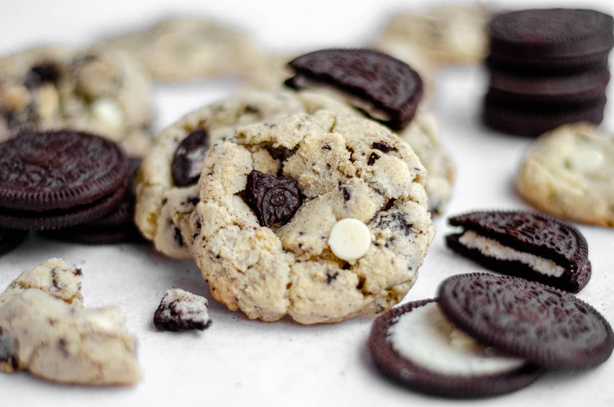 cookies and cream cookies on a white surface with oreo cookies scattered around it