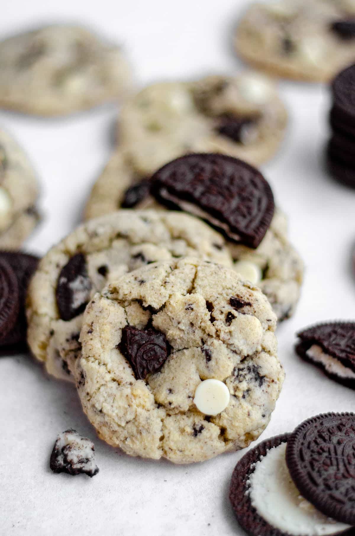 cookies and cream cookies on a white surface with oreo cookies scattered around it