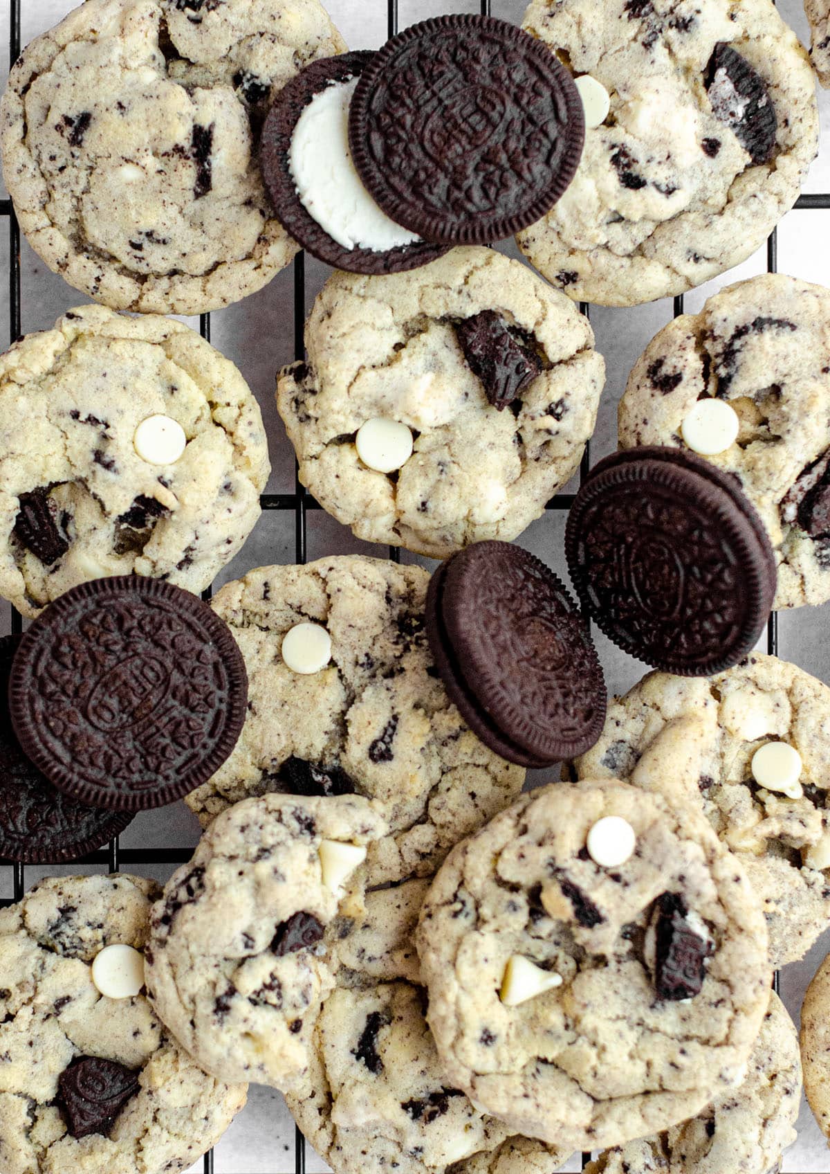 aerial photo of cookies and cream cookies on a cooling rack with oreos scattered around them