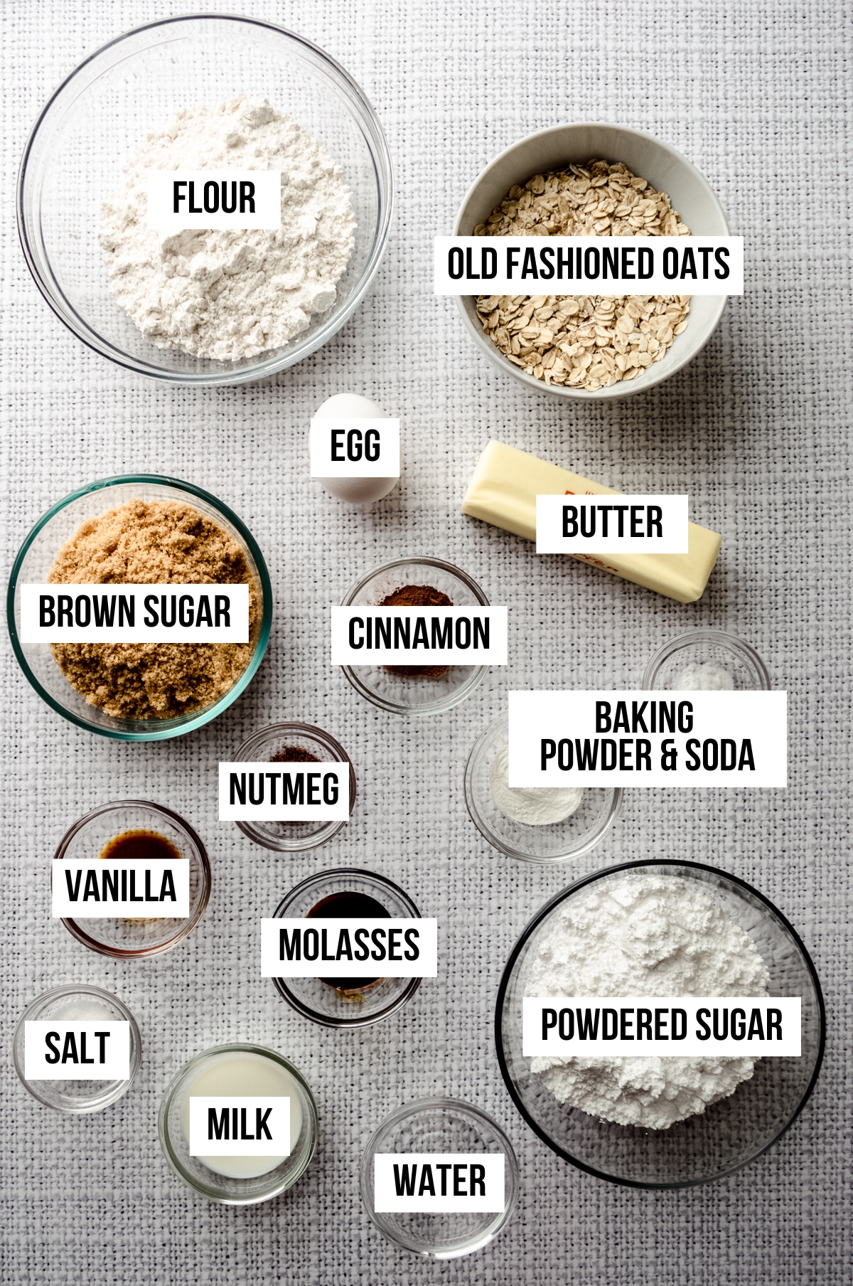 Aerial photo of ingredients to make molasses iced oatmeal cookies with text overlay labeling each ingredient.