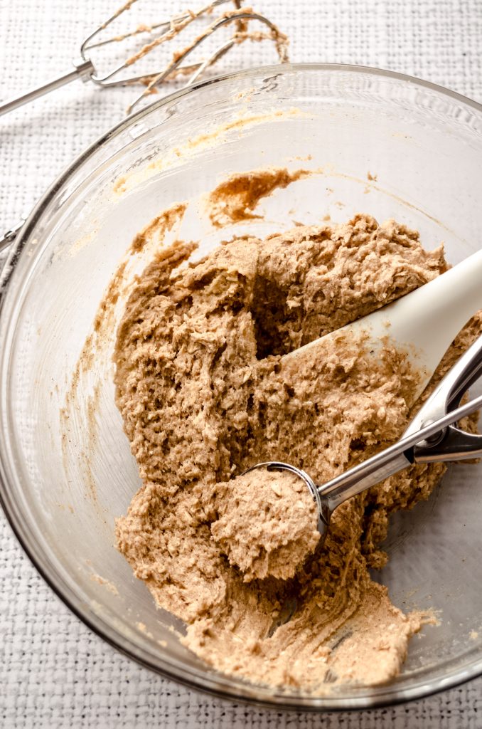 A cookie scoop filled with oatmeal cookie dough in a bowl.