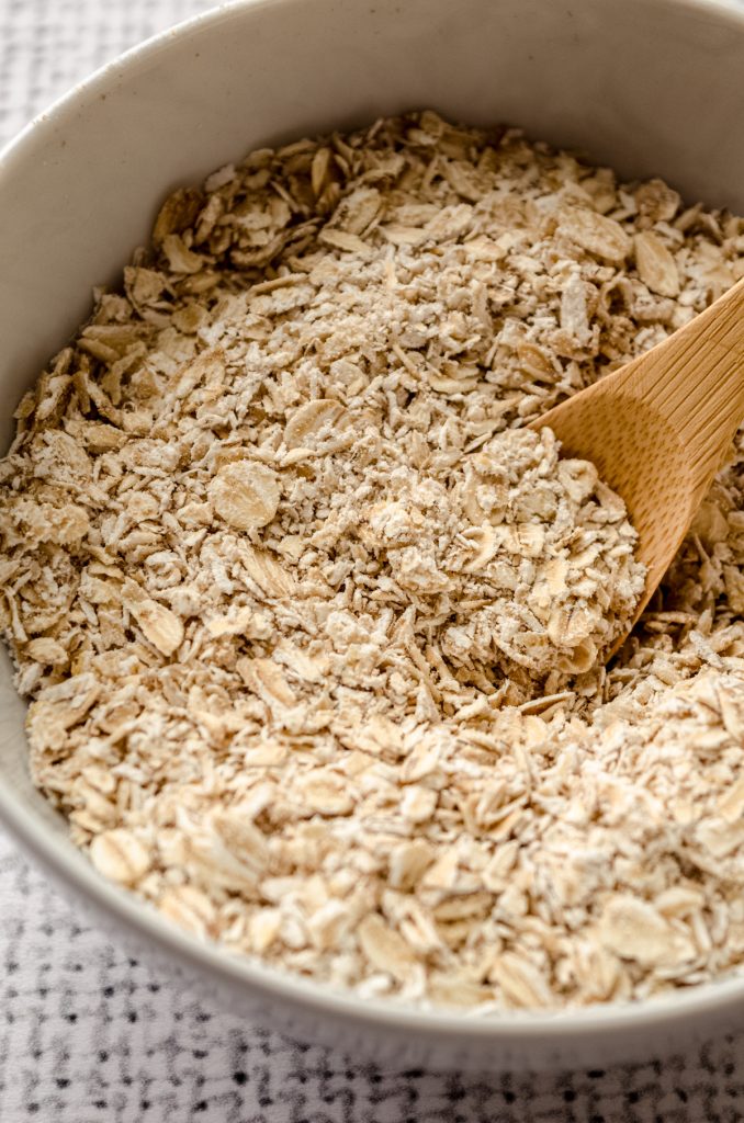 A bowl of oats with a wooden spoon in the bowl.