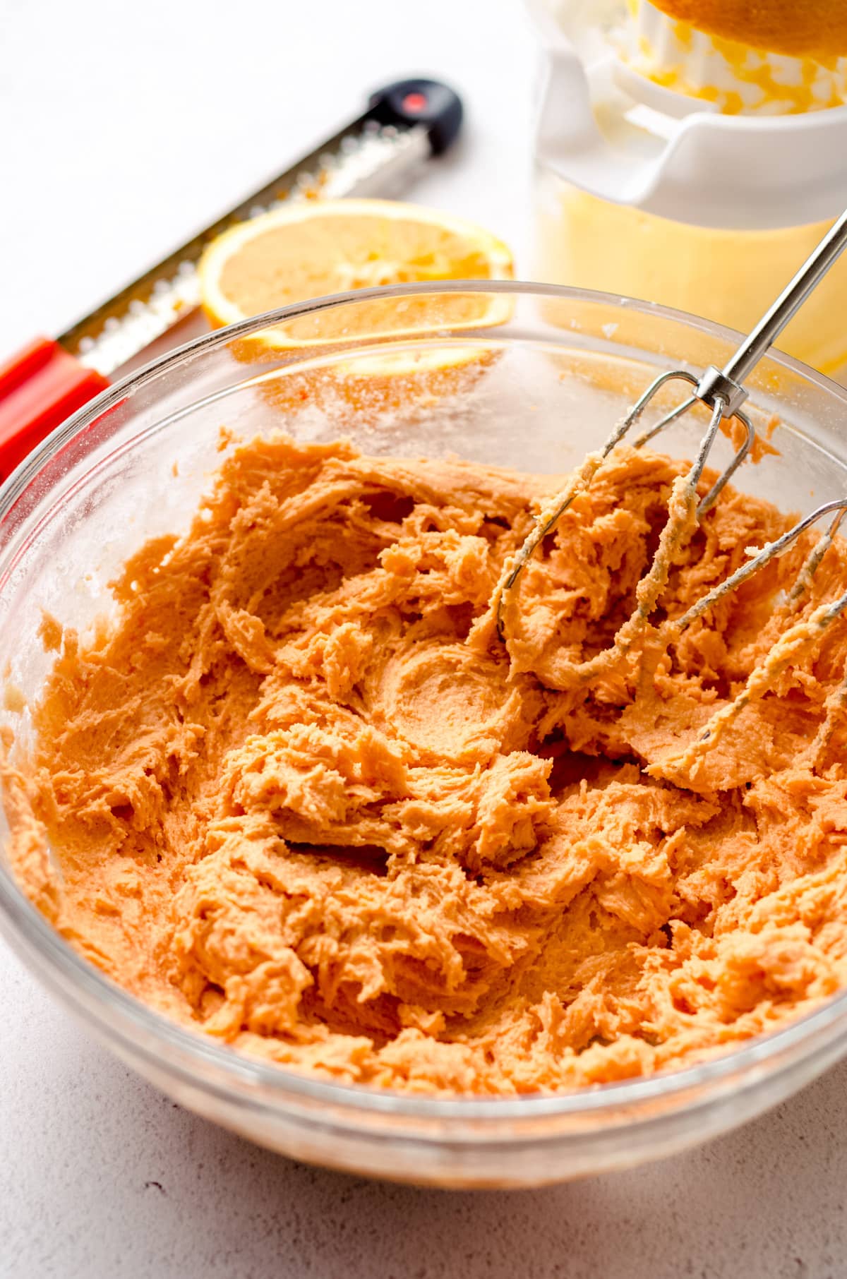 orange creamsicle cookie dough in a bowl with mixer beaters