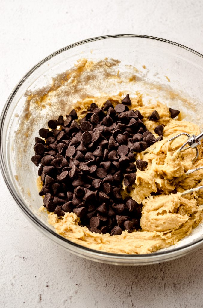 A bowl of cookie dough with chocolate chips poured into it.