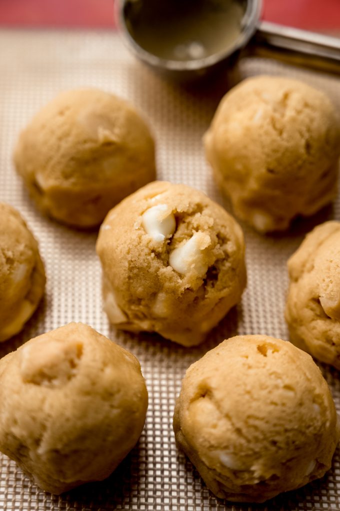 White chocolate macadamia nut cookie dough rolled into balls and sitting on a baking sheet.