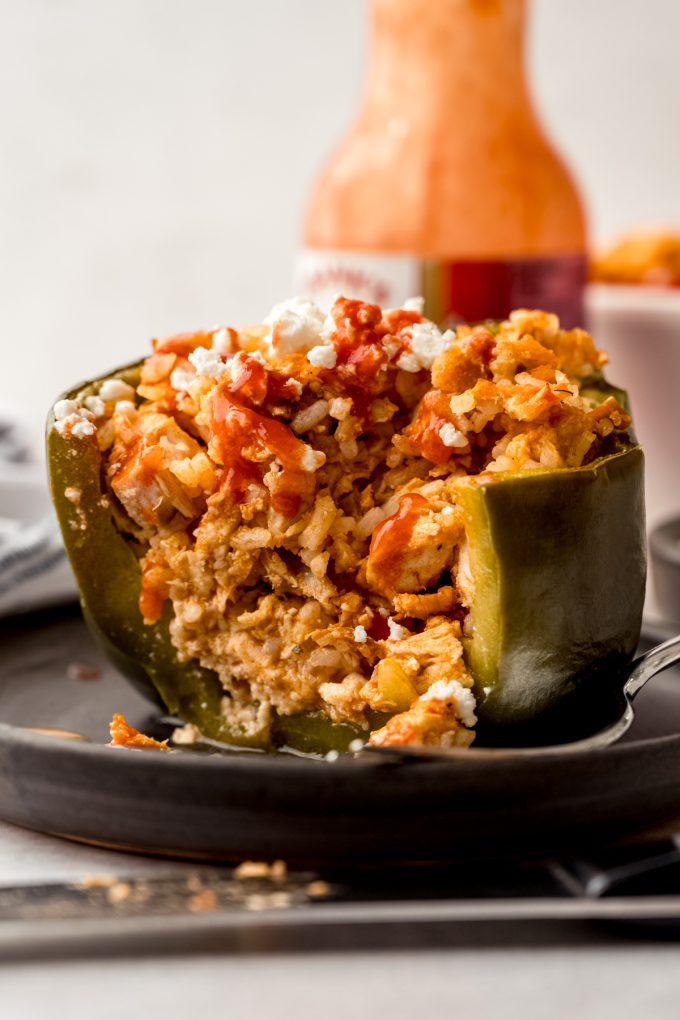 A buffalo chicken stuffed pepper on a plate and a bite has been taken out of it.