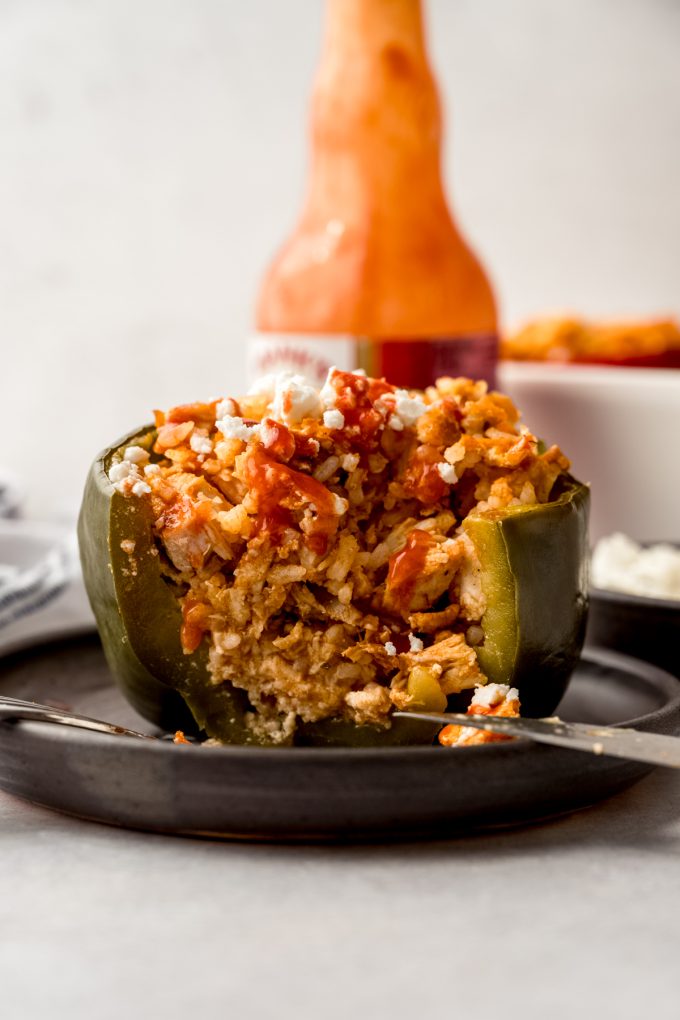 A buffalo chicken stuffed pepper on a plate and a bite has been taken out of it.