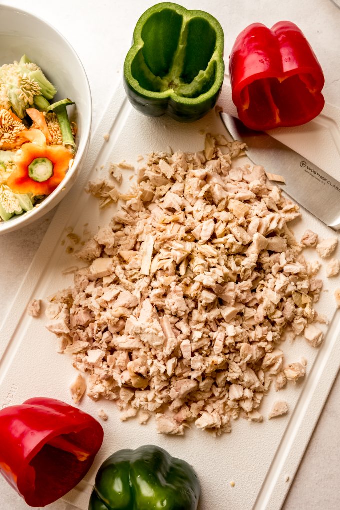 Aerial photo of chopped chicken and cut bell peppers on a cutting board.