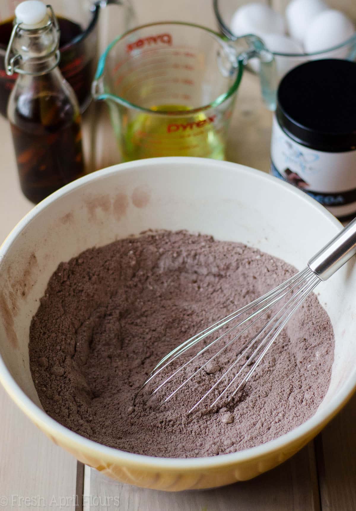 dry batter for simple chocolate cupcakes in a ceramic bowl with a metal whisk