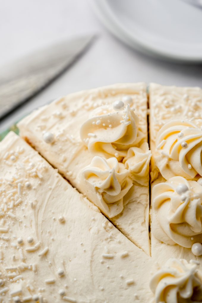 White cake on a cake stand that has been sliced.