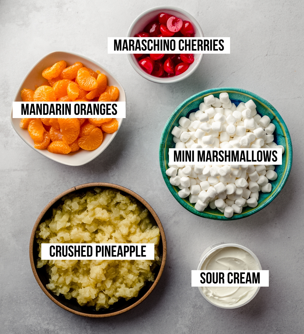 Aerial photo of ingredients for ambrosia salad labeled with text overlay to identify each ingredient.