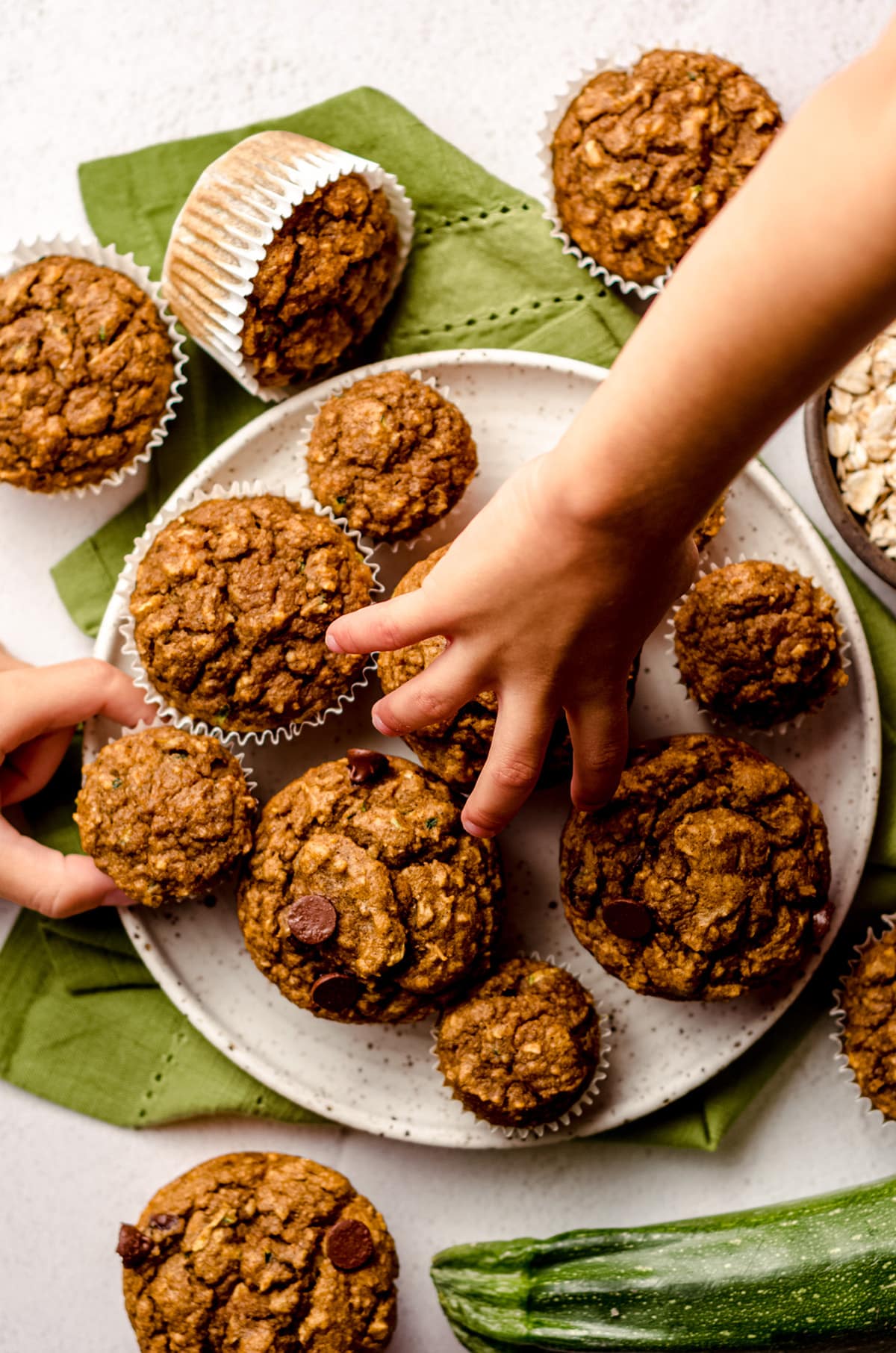 children's hands grabbing toddler muffins from a plate