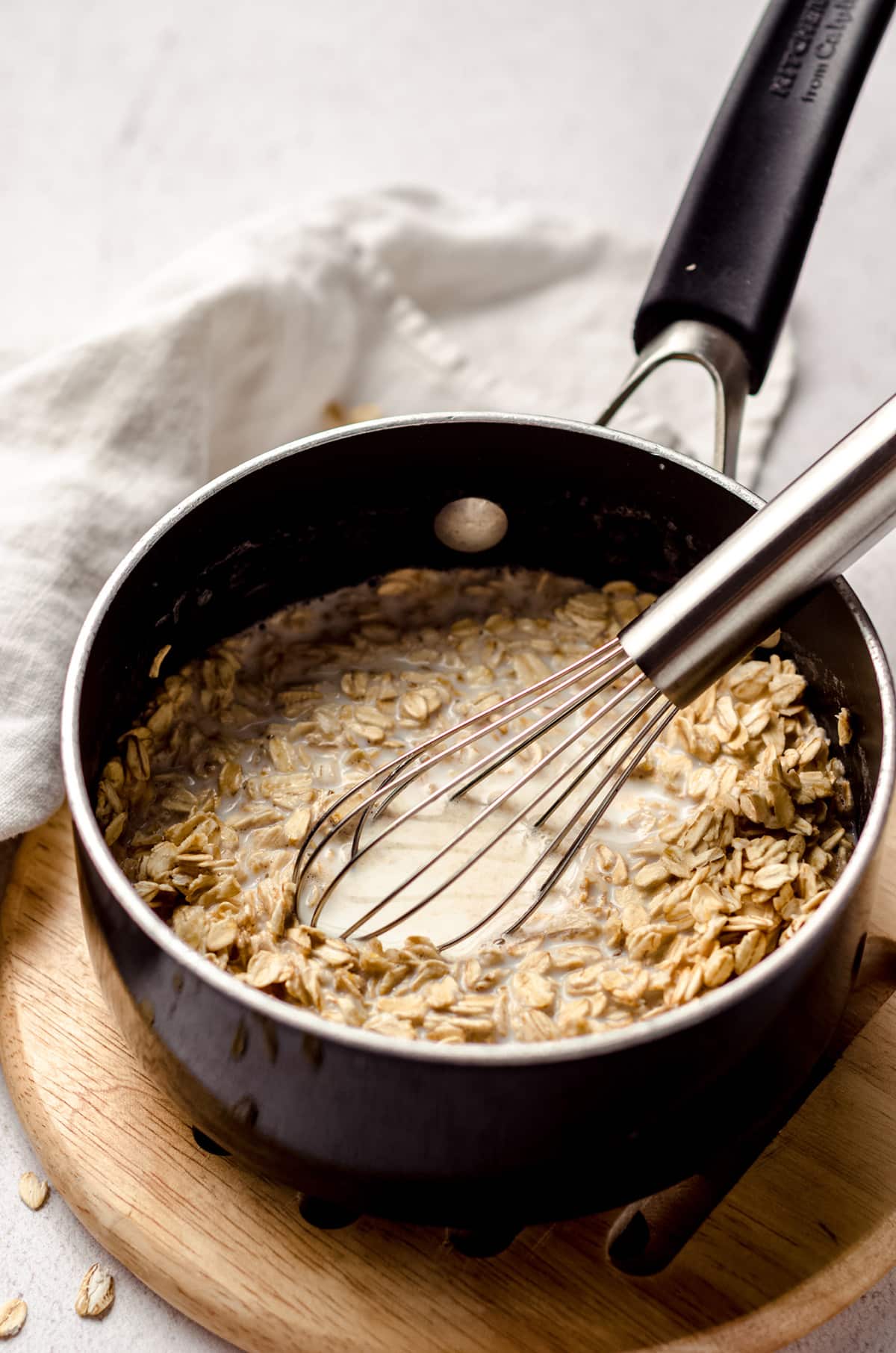 oats and milk in a saucepan with a whisk