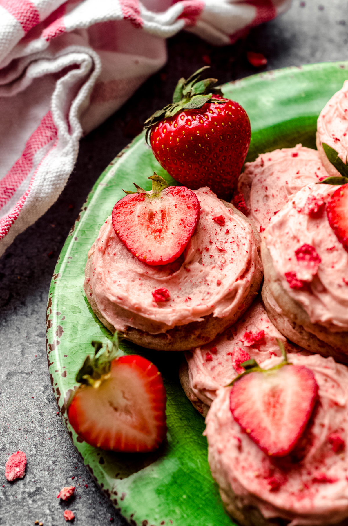 Frosted strawberry cookies on a green plate.