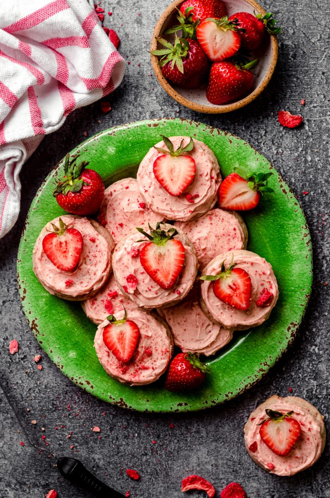 Frosted strawberry cookies on a green plate.