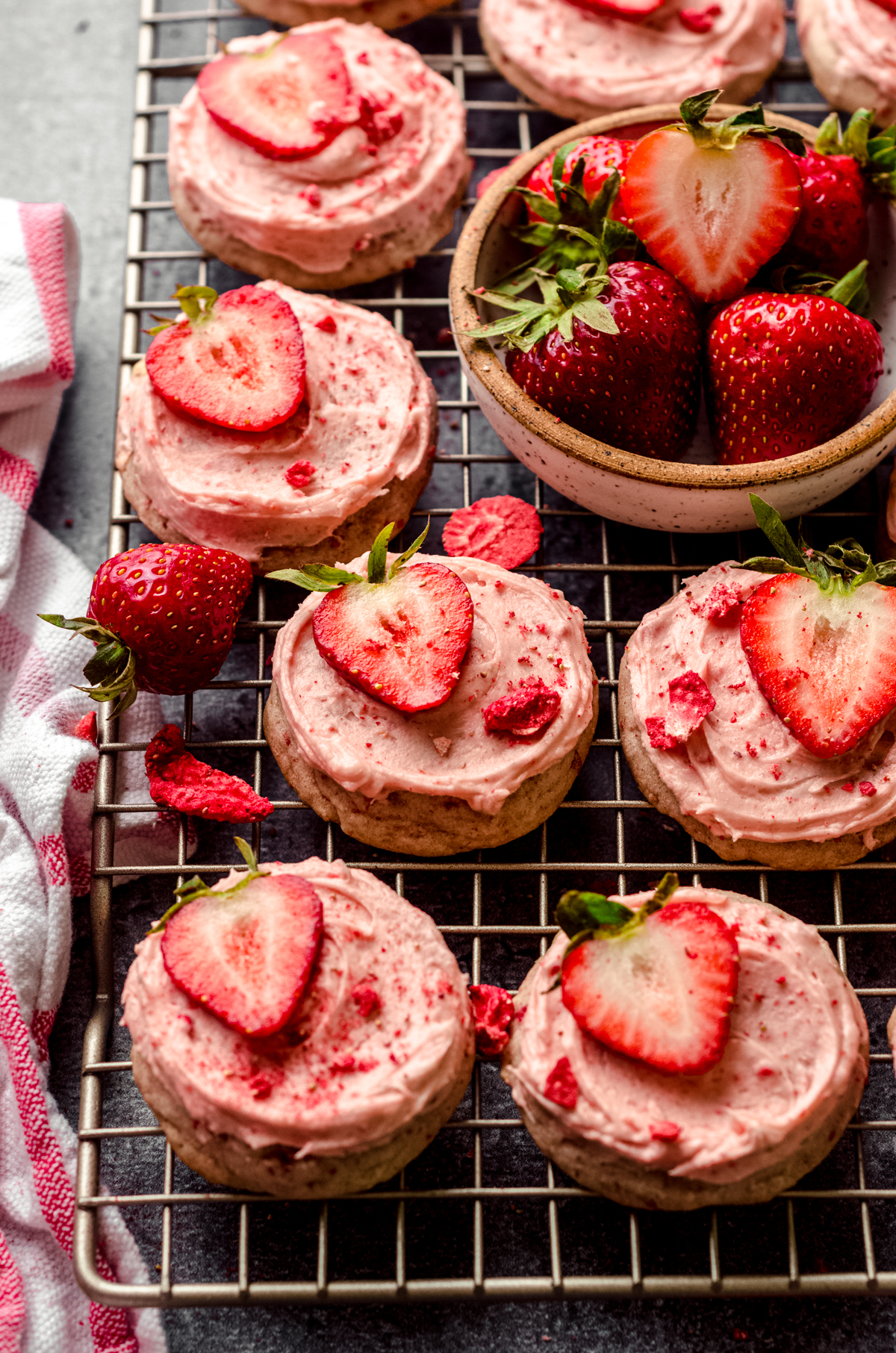 Frosted strawberry cookies on a wire cooling rack.