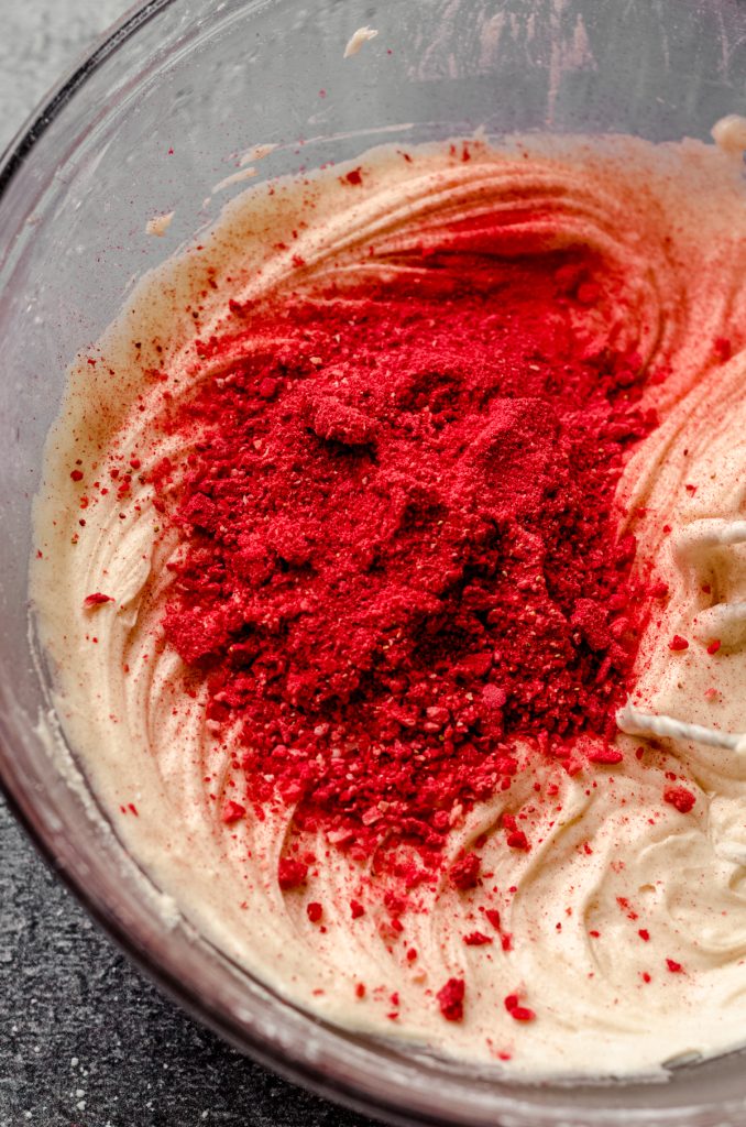 Bowl of vanilla buttercream with strawberry powder in it so it can be turned into strawberry buttercream.