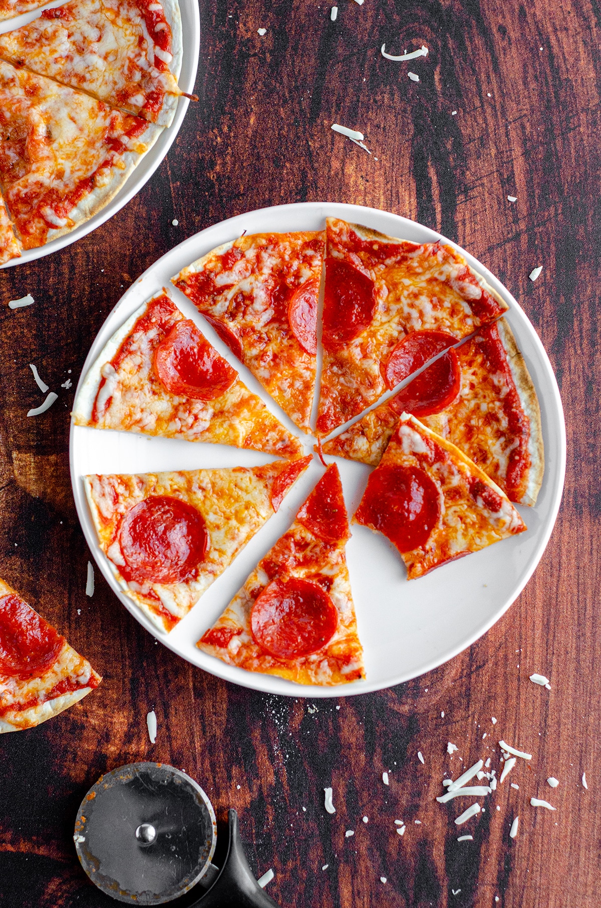 aerial photo of a personal tortilla pizza on a plate cut into slices and one slice has a bite taken out of it