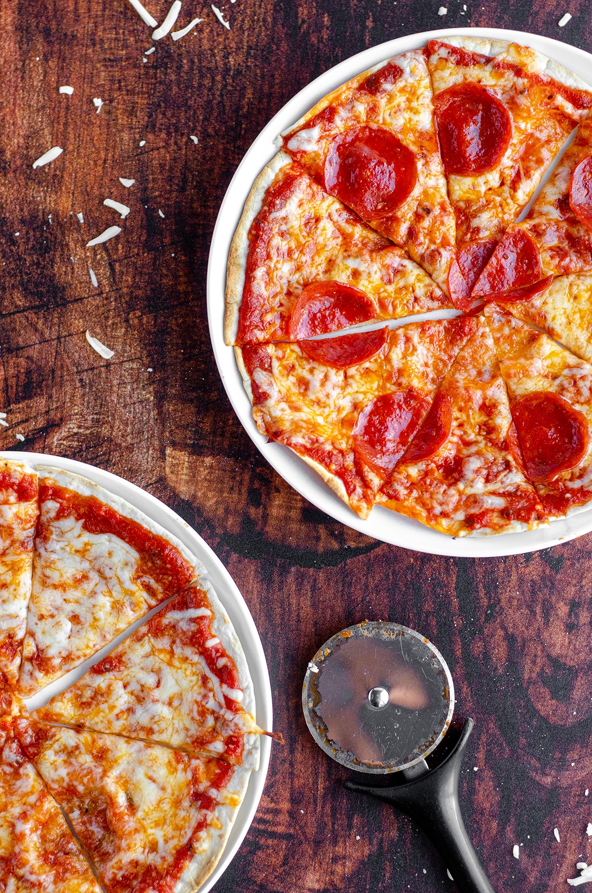 aerial photo of personal tortilla pizzas on plates cut into slices