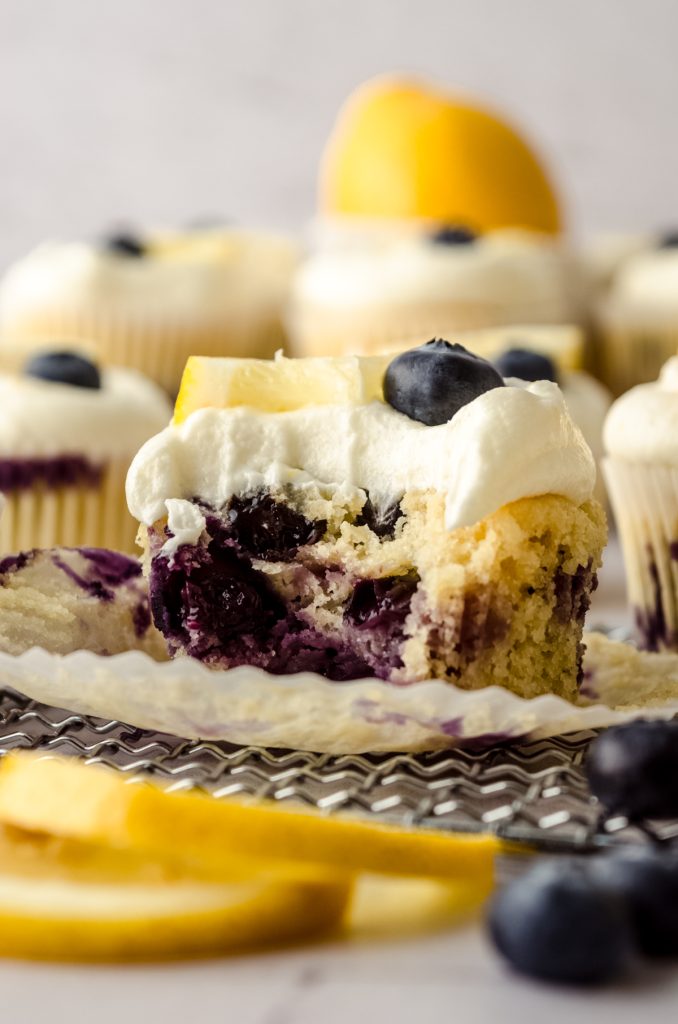 A lemon blueberry cupcake with a bite taken out of it.