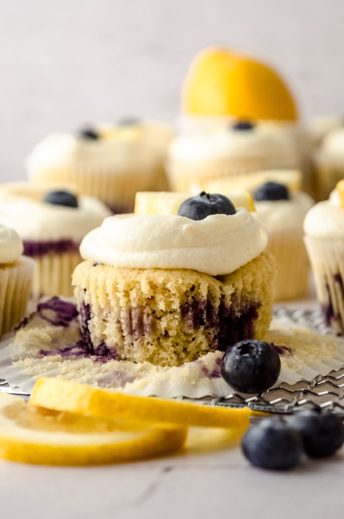 A lemon blueberry cupcake with the wrapper pulled down to the sides.