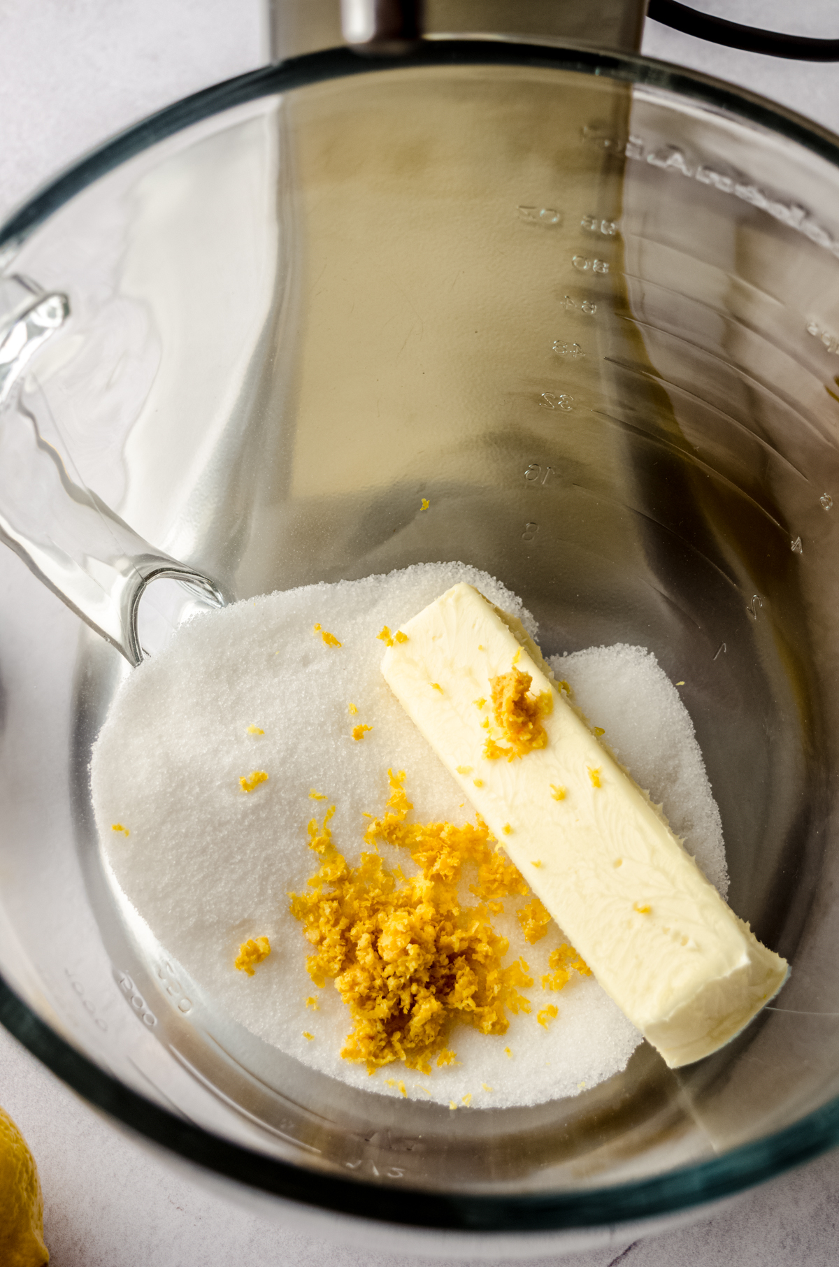 The bowl of a stand mixer with butter, sugar, and lemon zest in it.