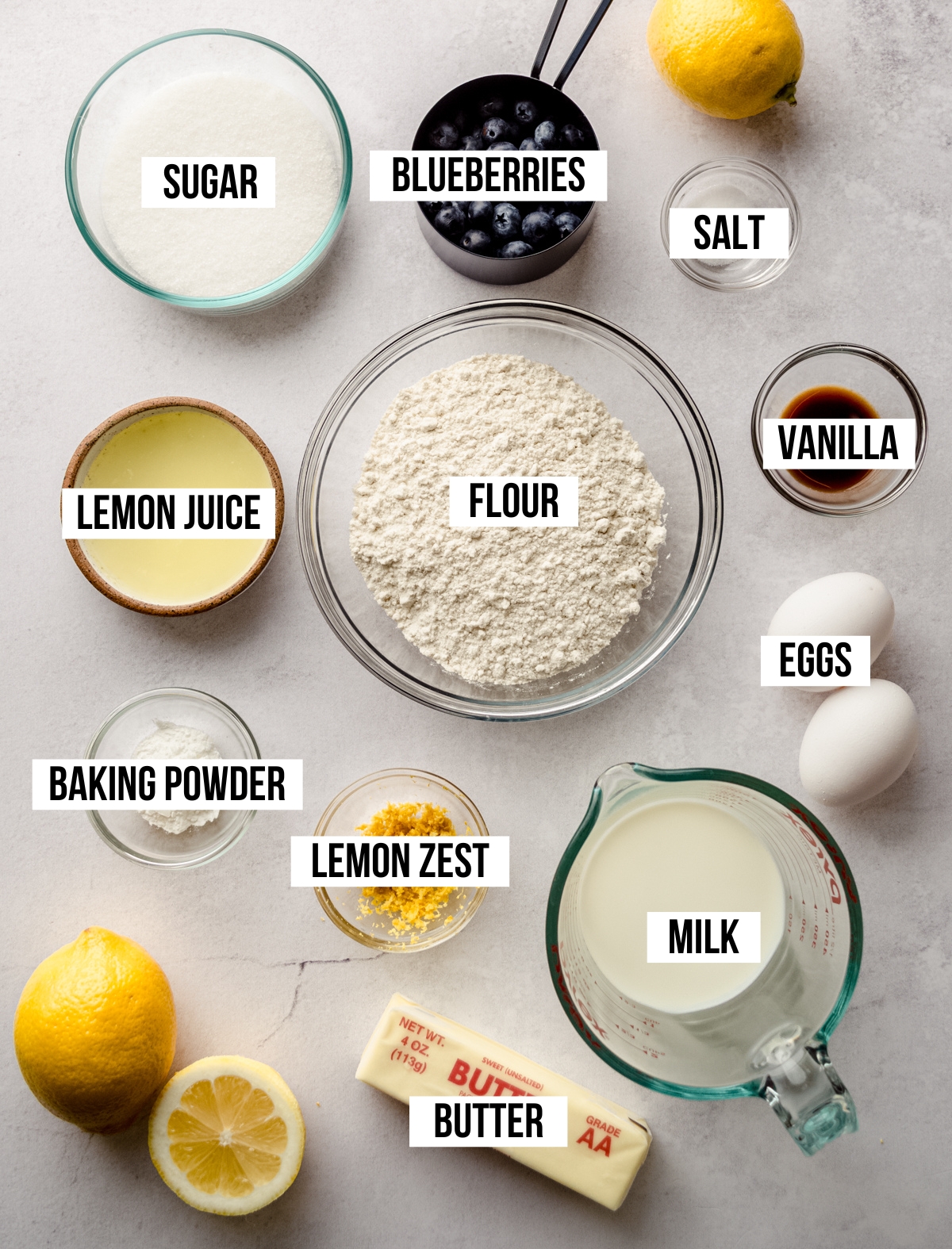 Aerial photo of ingredients for lemon blueberry cupcakes with text overlay labeling each ingredient.