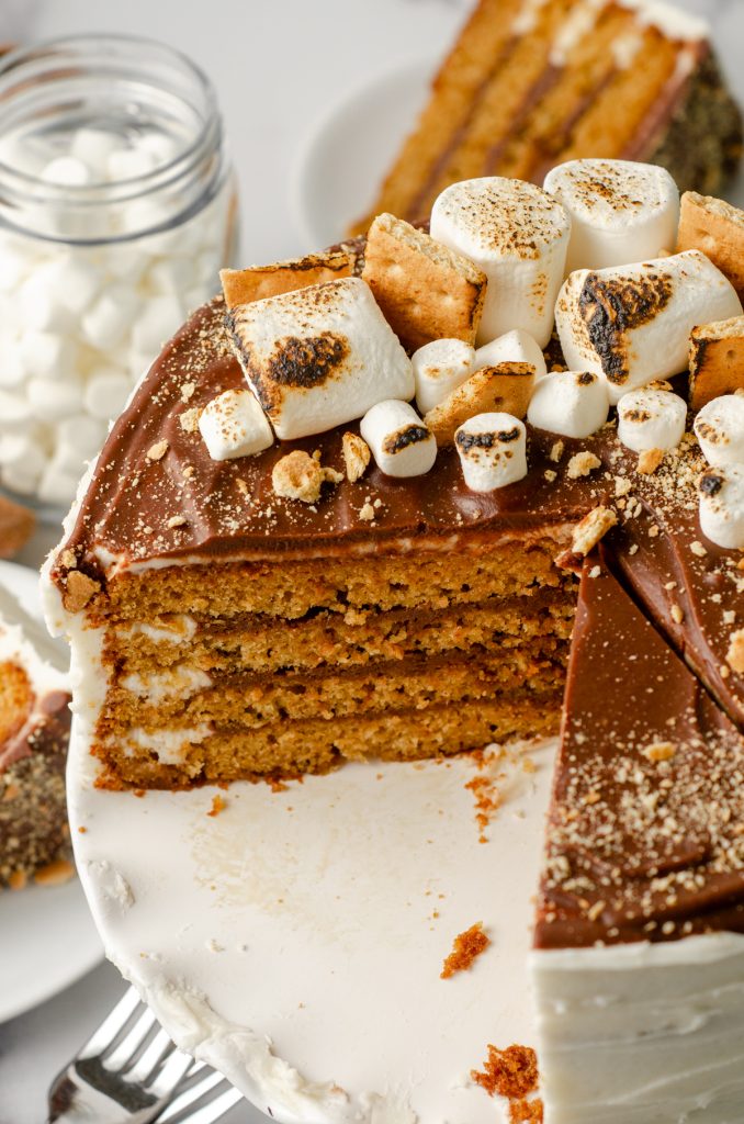 S'mores cake on a cake platter. It has been sliced so you can see the inside layers.