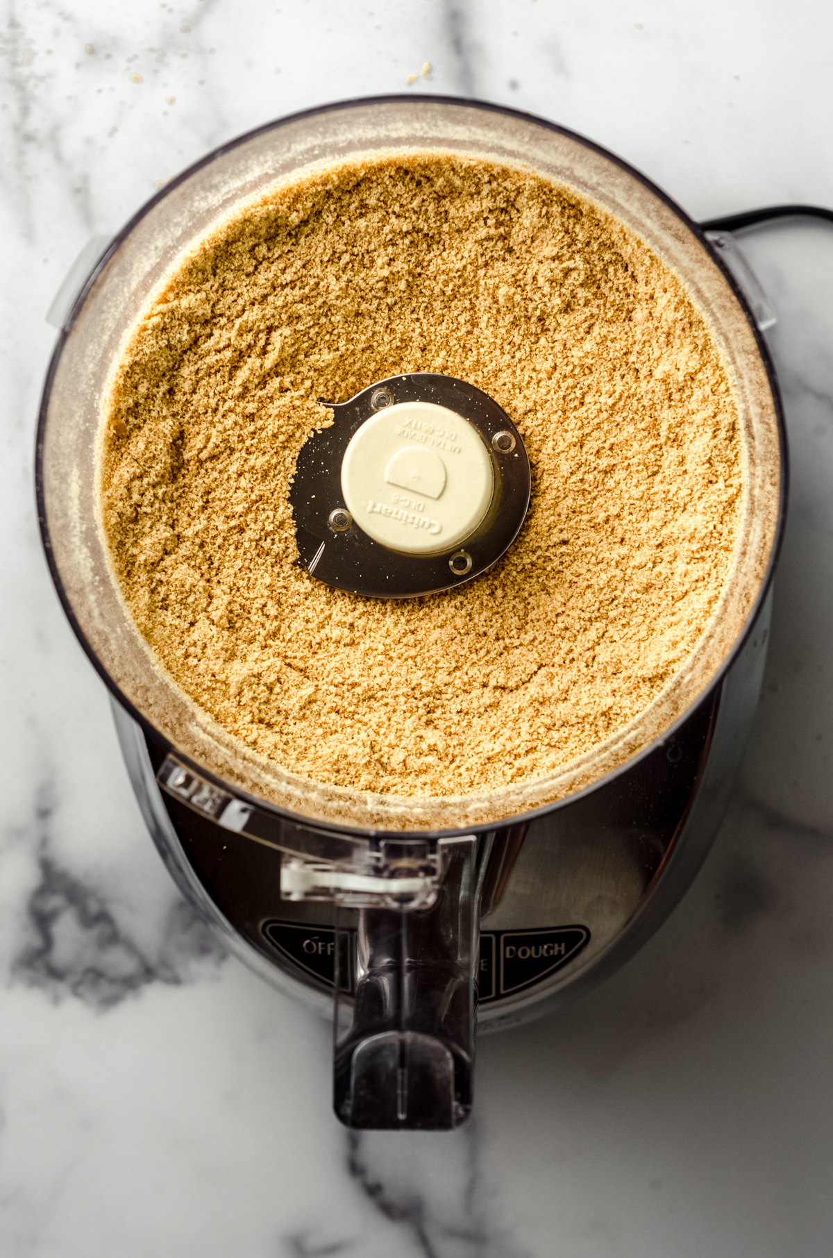 Aerial photo of crushed graham crackers in a food processor.