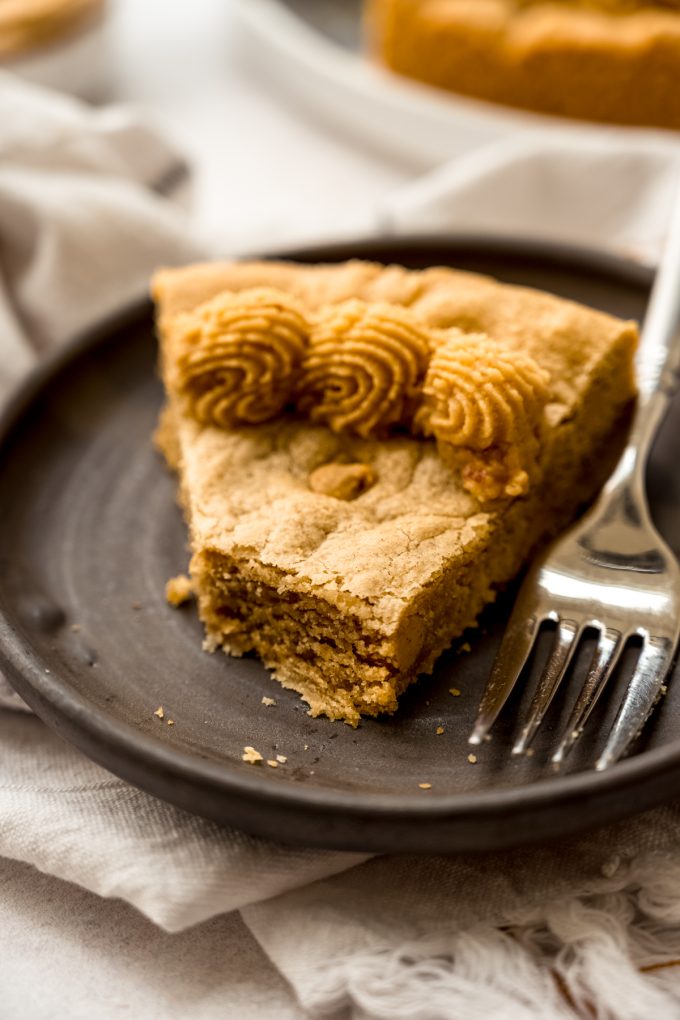 A slice of peanut butter cookie cake on a plate with a fork.