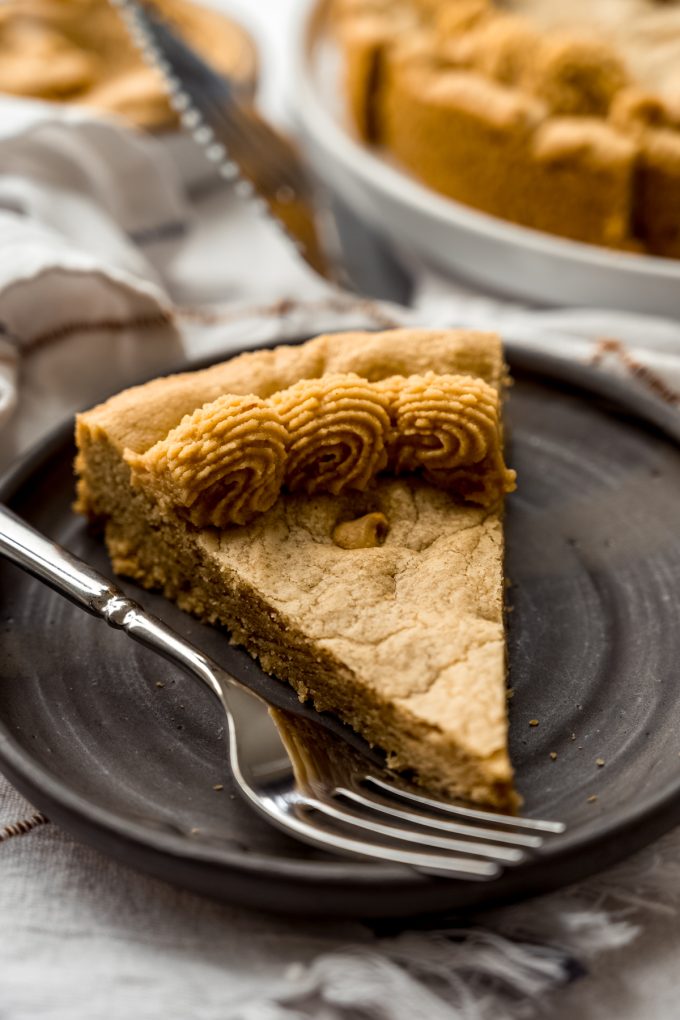 A slice of peanut butter cookie cake on a plate with a fork.