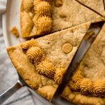 Aerial photo of someone removing a slice of peanut butter cookie cake with a server.