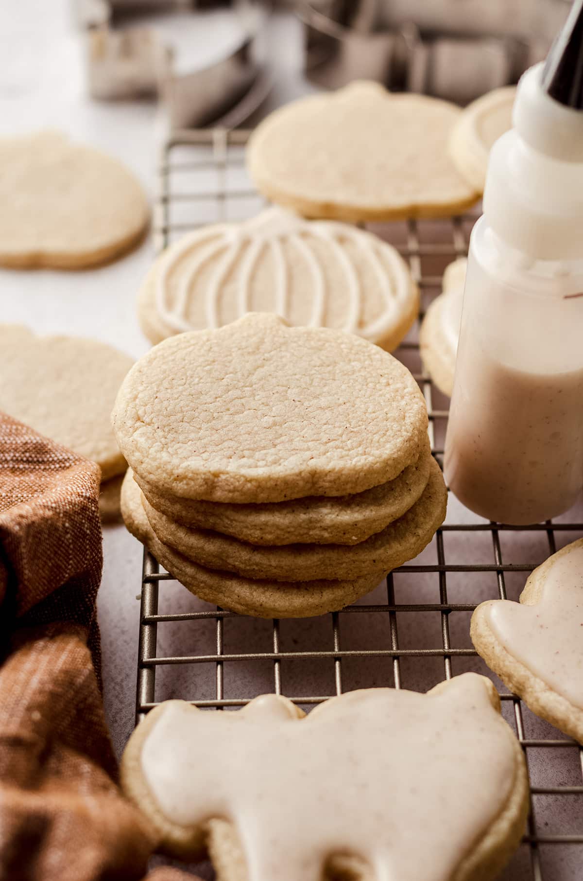stack of pumpkin shaped sugar cookies on a cooling rack