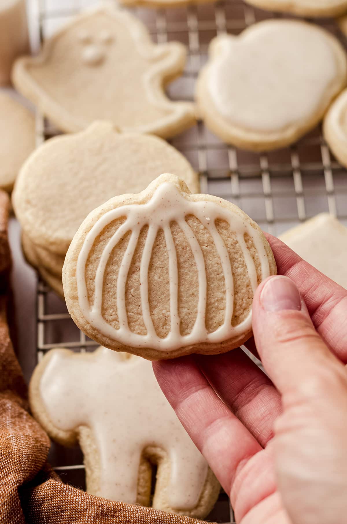 hand holding a pumpkin shaped cookie