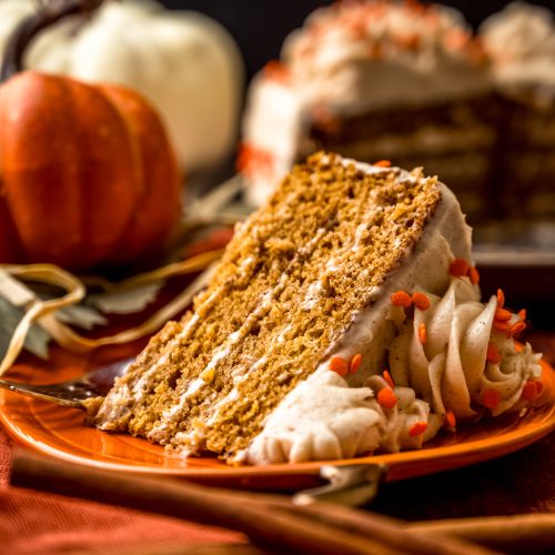 A slice of pumpkin layer cake on a plate with a fork.