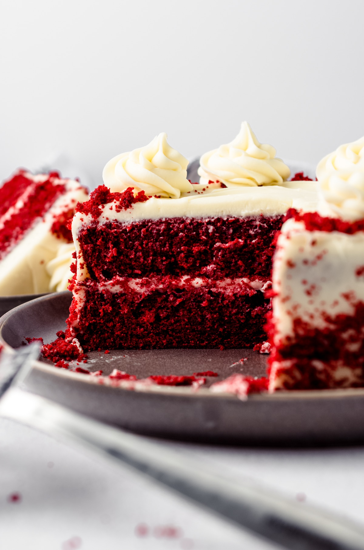 Side view of a sliced red velvet cake. You can see the inside of the cake and the layer of cream cheese frosting between the cake layers.