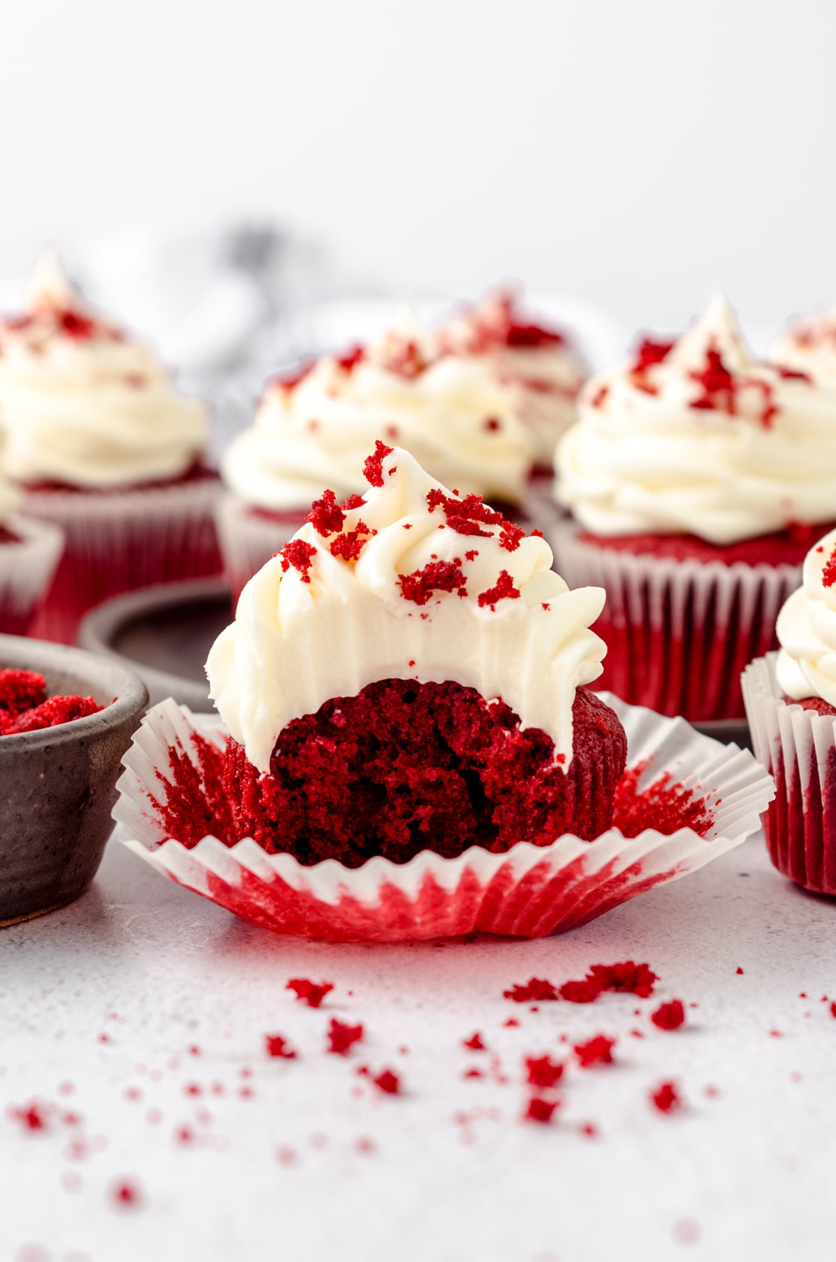 A red velvet cupcake with cream cheese frosting with a bite taken out of it.