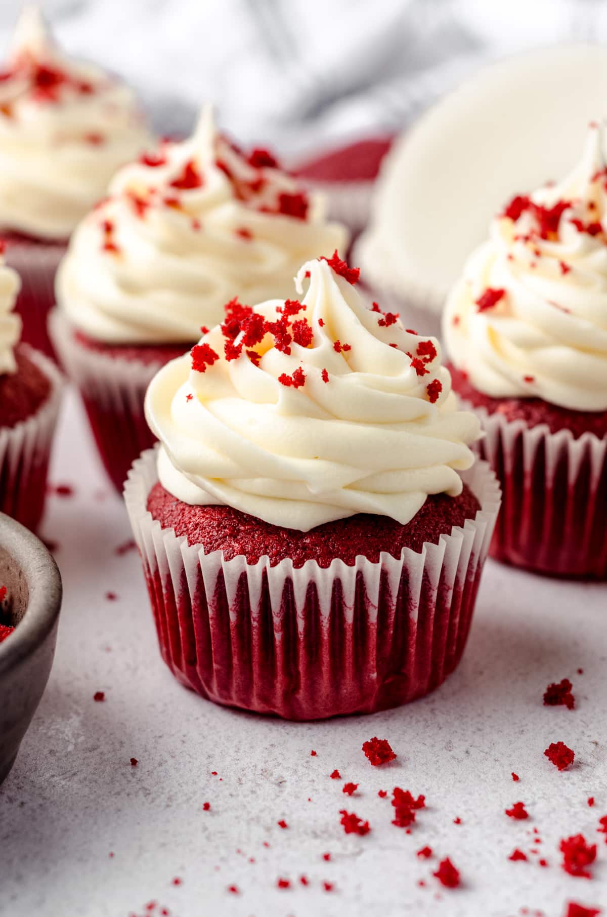 Red velvet cupcakes with cream cheese frosting and red velvet crumbs on top.