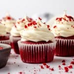 Red velvet cupcakes with cream cheese frosting and red velvet crumbs on top.