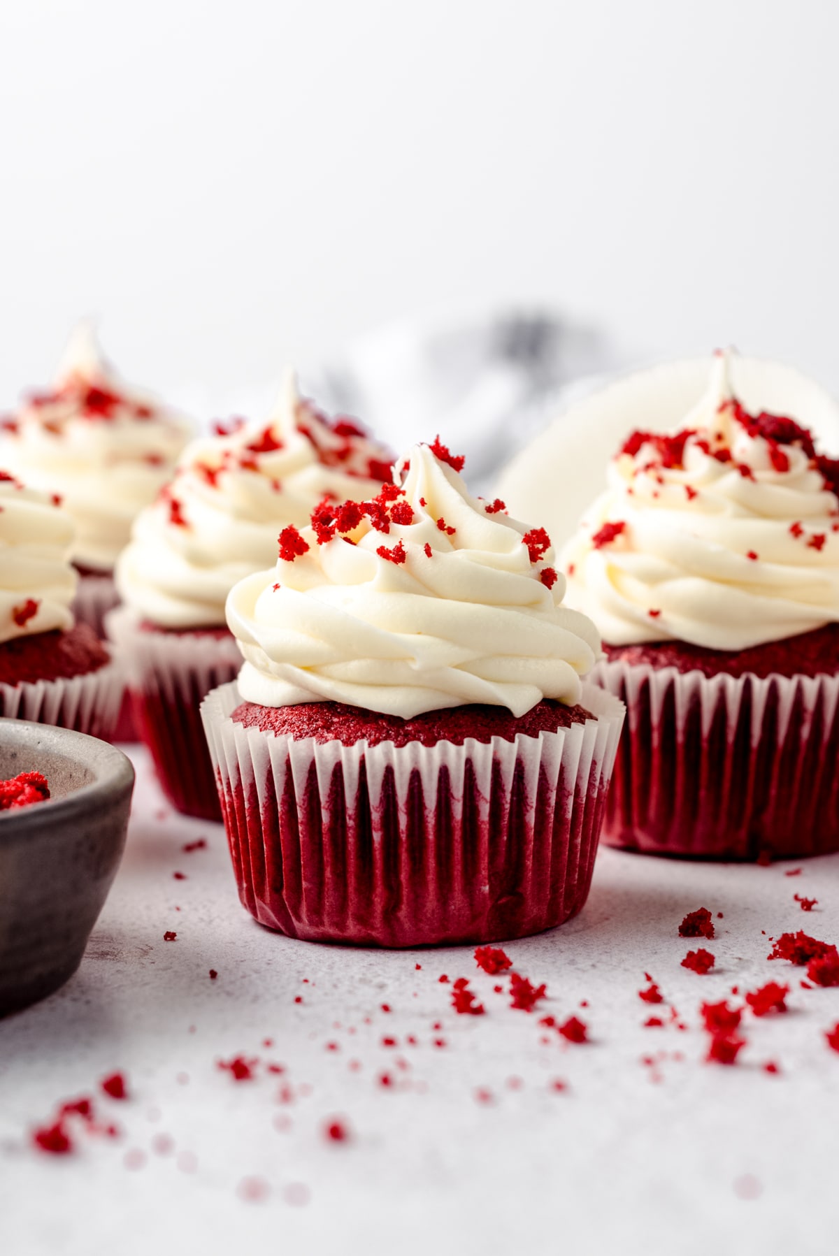 Red velvet cupcakes with cream cheese frosting and red velvet crumbs on top.