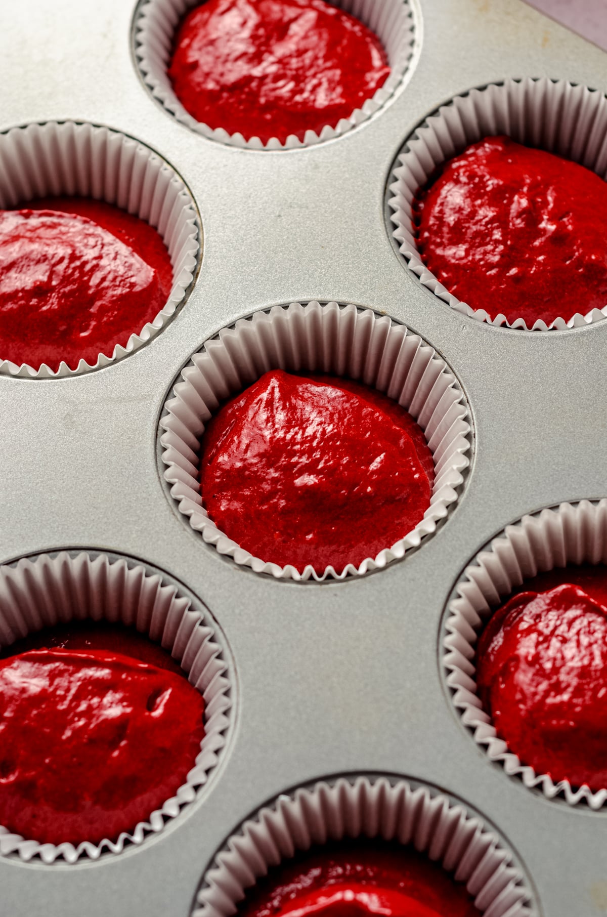 Red velvet cupcake batter in cupcake liners ready to be baked.