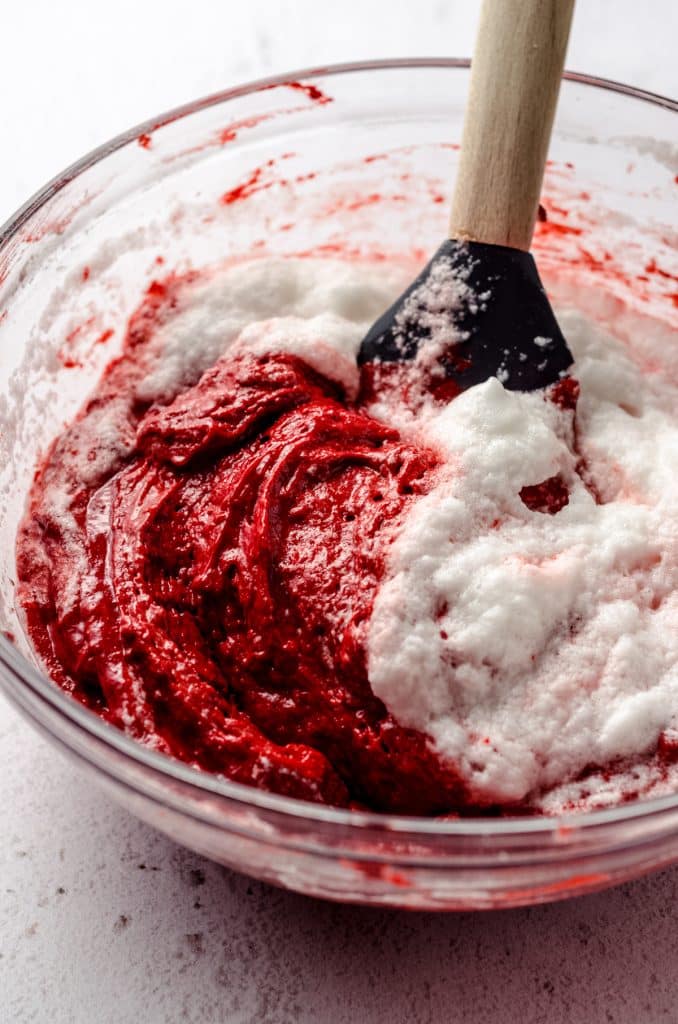 Folding egg whites into red velvet cupcake batter.