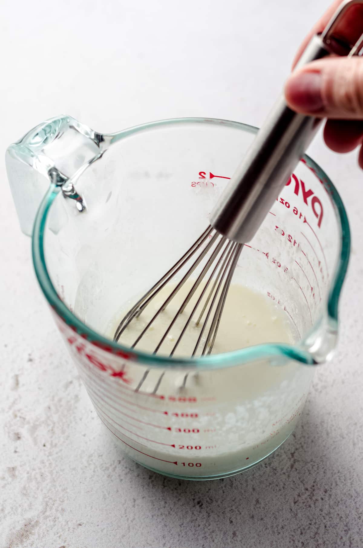 Whisking vinegar into milk to make buttermilk.